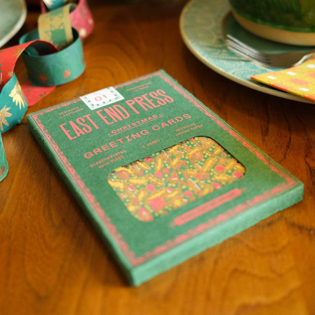 Green box of tea on a wooden table with decorative items in the background