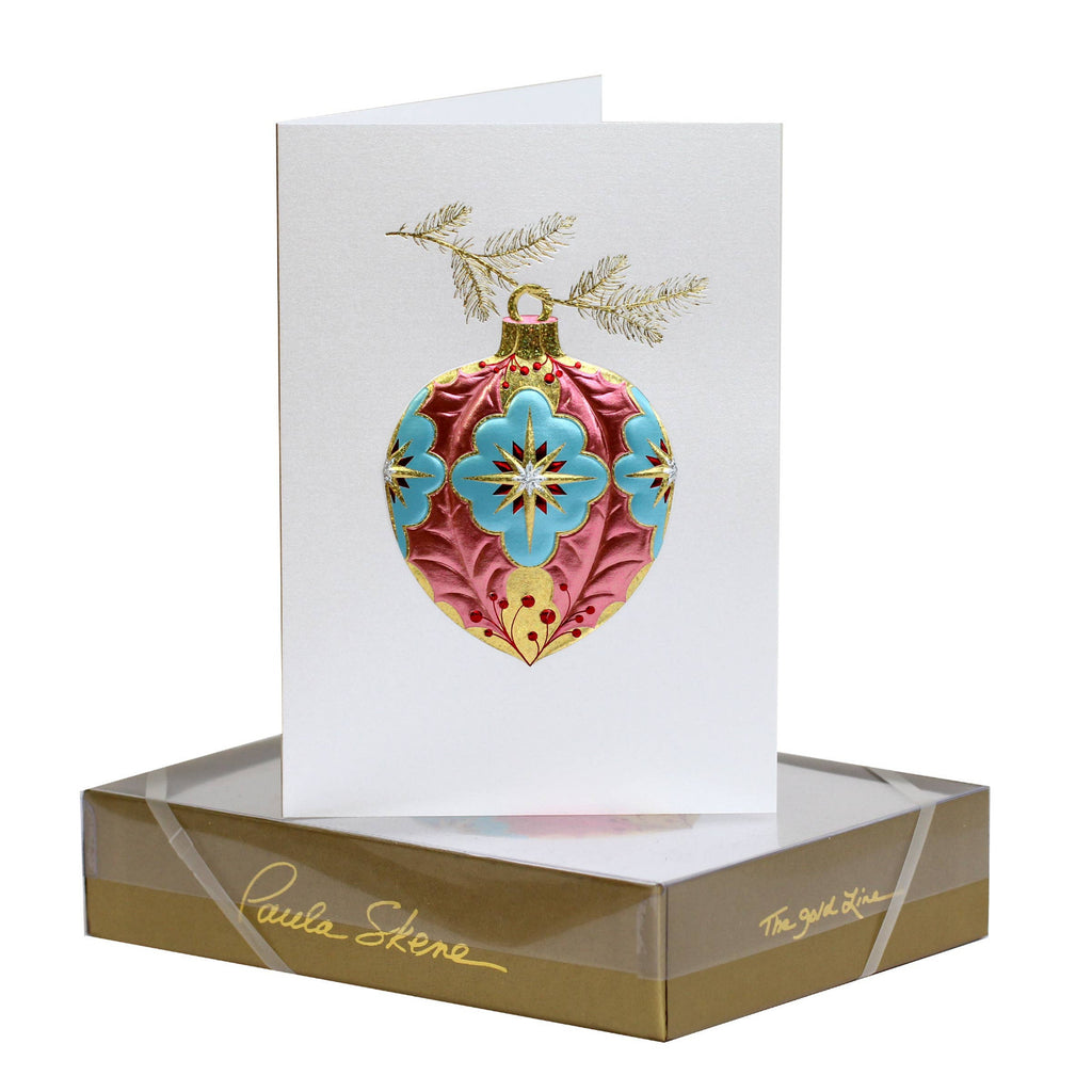 Decorative Christmas ornament card with gold and blue design on a white card, displayed in a gold box.