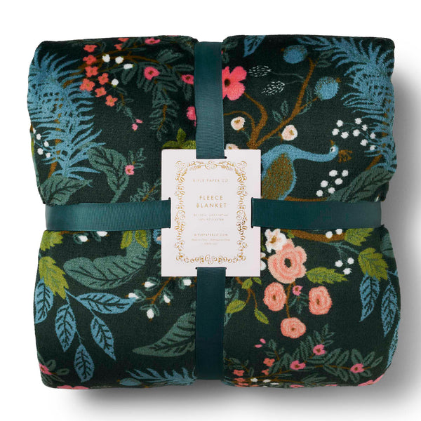 Folded floral blanket with a visible tag on a white background