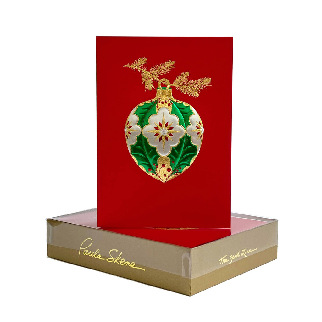 Decorative Christmas ornament card with gold and green design on a red card, featuring Paula Skene branding.