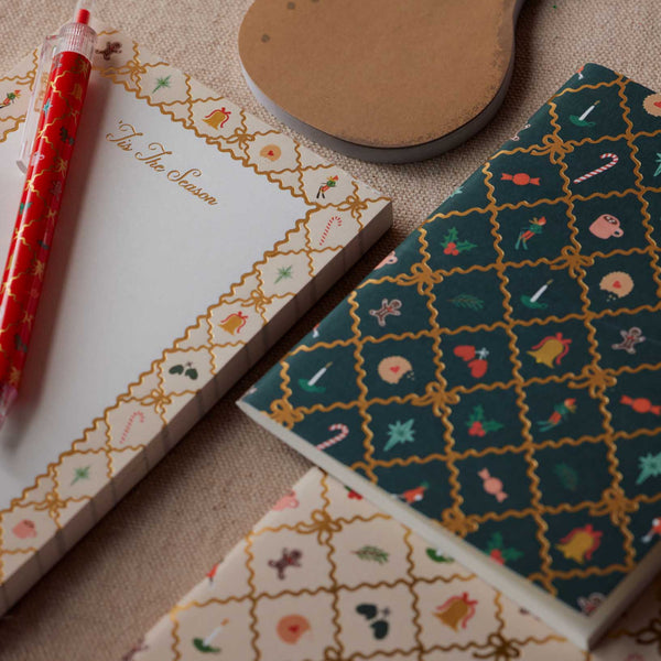 Notebooks with decorative covers and a pen on a textured surface
