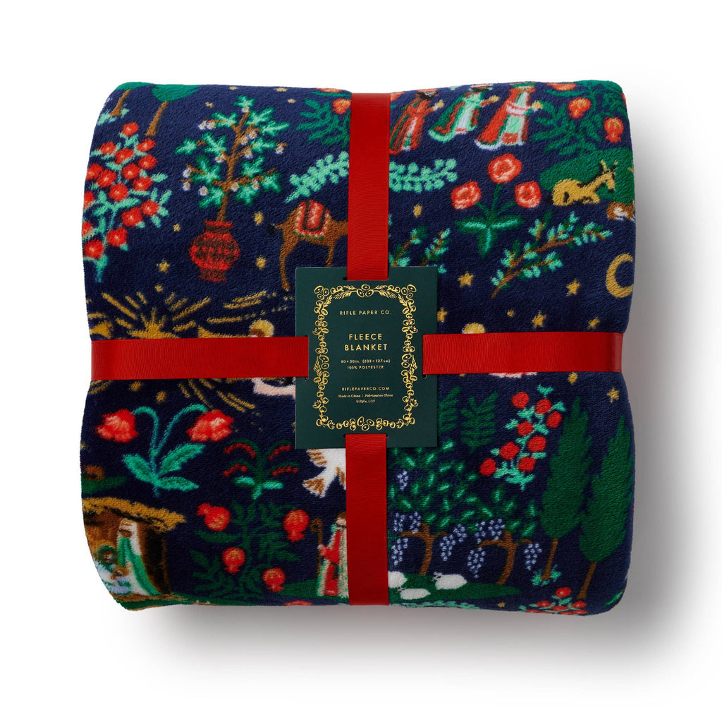 Folded fleece blanket with festive pattern and red ribbon on a white background