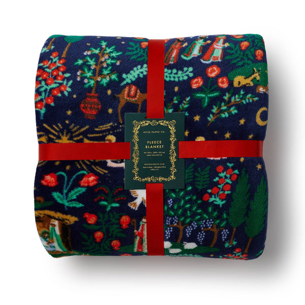 Folded fleece blanket with festive pattern and red ribbon on a white background