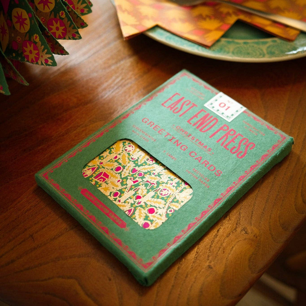 Green box with floral design on a wooden table with a tea set in the background