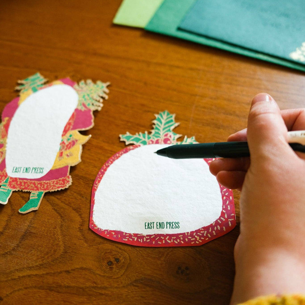 Hand using a pen on a white card with 'Last End Press' branding on a wooden surface.