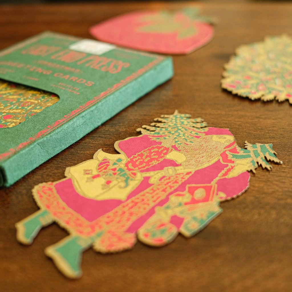 Colorful paper cutouts on a wooden surface with a book titled 'Lucky Cats' in the background.