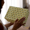 Person holding a box with floral pattern against a blurred background