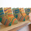 Colorful patterned socks on a wooden surface with a person's hand reaching out.