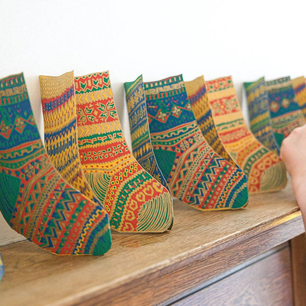 Colorful patterned socks on a wooden surface with a person's hand reaching out.