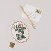 Decorative card with floral design, pen, and envelope on a light background