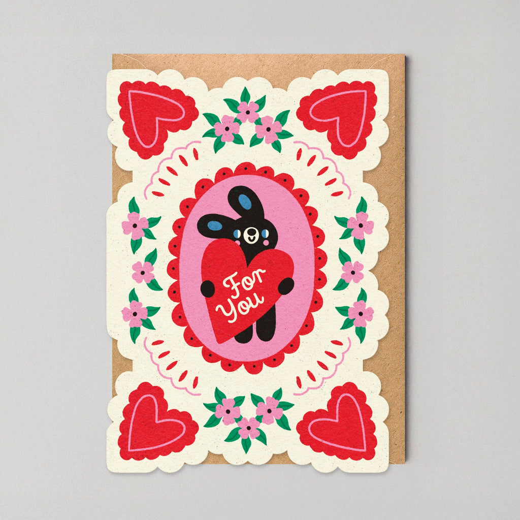 Greeting card with a cartoon character holding a heart and decorative border on a gray background