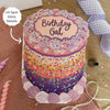 Decorative birthday card with a cake design and 'Birthday Gal' text on a wooden surface.
