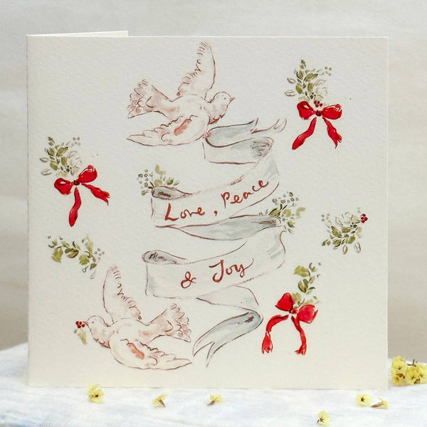Greeting card with doves, ribbons, and 'Love, Peace & Joy' text on a white background.