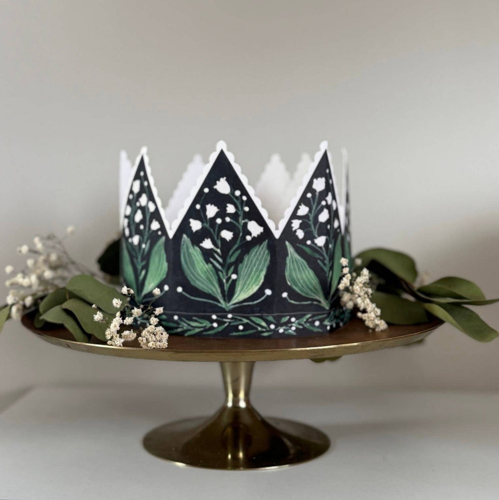 Decorative paper crown with green leaf pattern on a white background