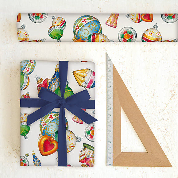 Gift wrapped in colorful paper with a blue ribbon, next to a ruler on a white surface.
