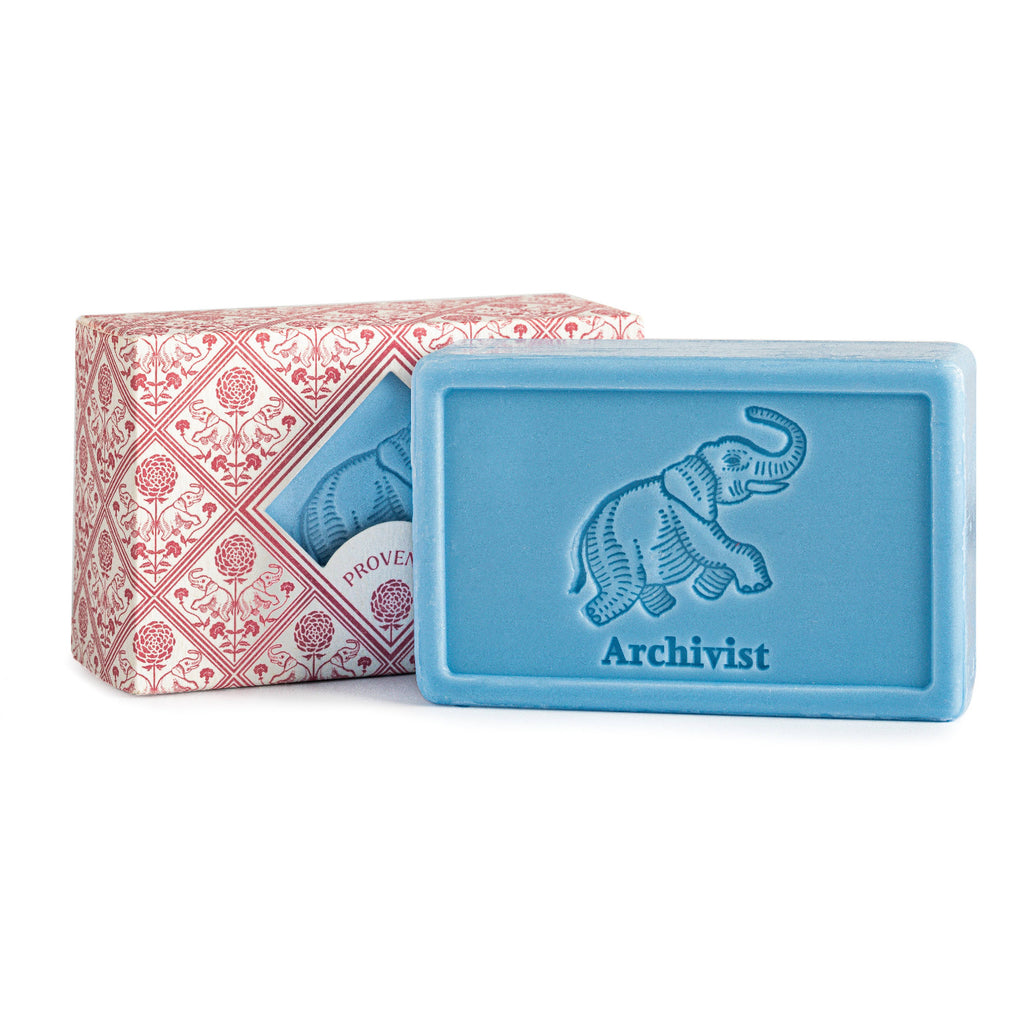 Blue soap bar with 'Archivist' branding and decorative packaging on a white background