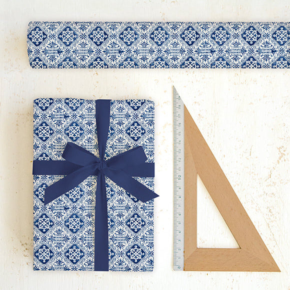 Blue and white patterned gift wrap with a bow and ruler on a light background