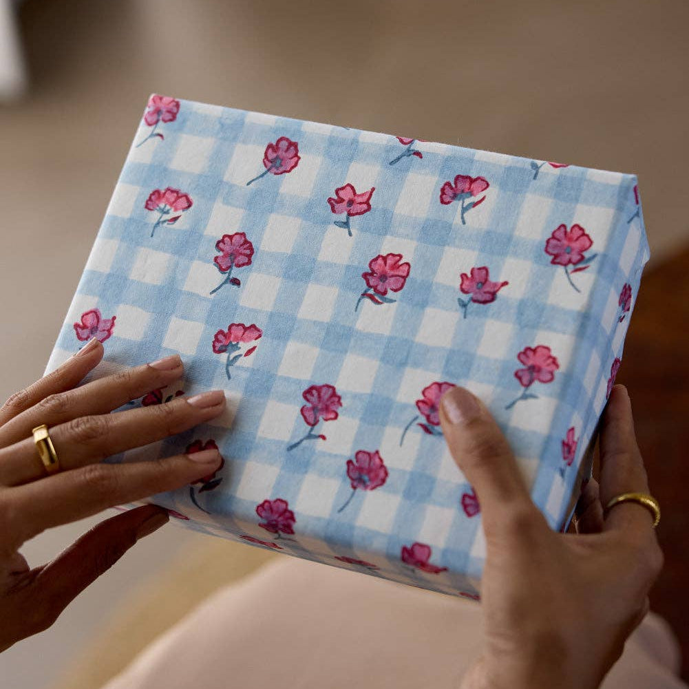 Person holding a box with blue checkered pattern and pink flowers