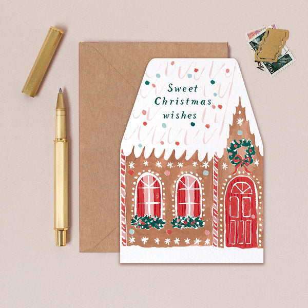 Greeting card with gingerbread house design and envelope on a beige background