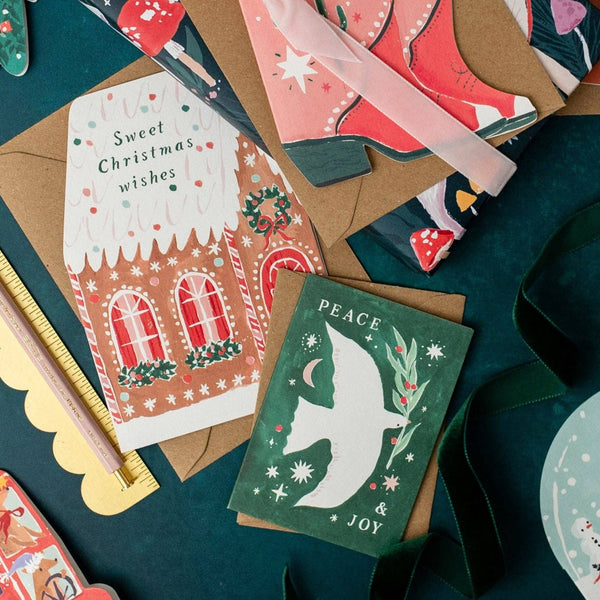 Collection of Christmas-themed greeting cards with decorative envelopes on a green surface.