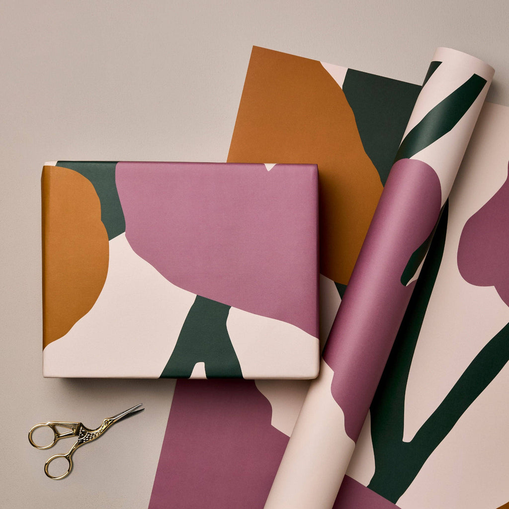 Gift wrap with abstract patterns and a pair of scissors on a beige background