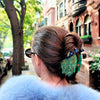 Person with styled hair and blue fur coat on a city street