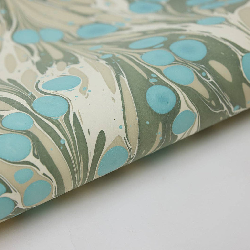 Marbled paper with blue and green patterns on a white background