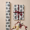 Gift wrapped in festive paper with a red ribbon, accompanied by scissors on a beige background.