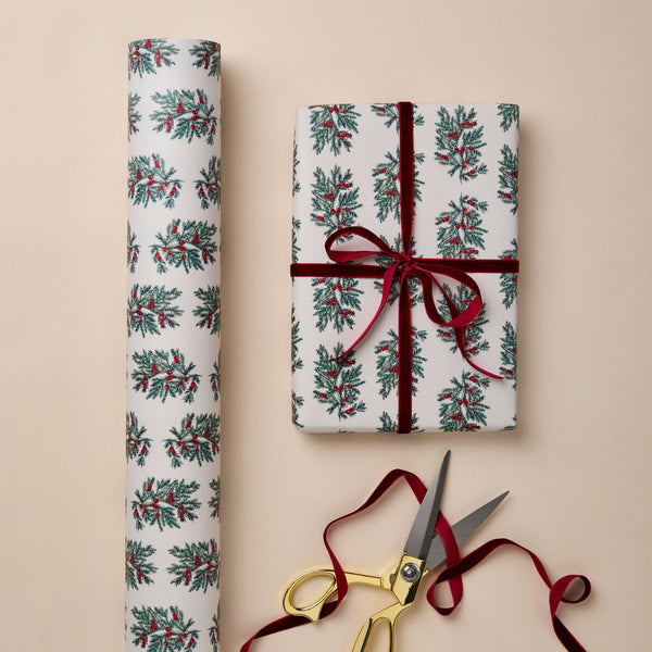 Gift wrapped in festive paper with a red ribbon, accompanied by scissors on a beige background.