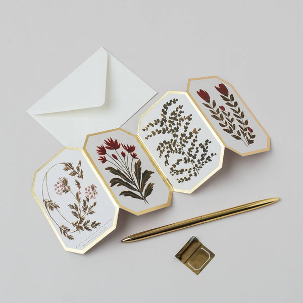 Set of floral cards with a gold pen and envelope on a light gray background