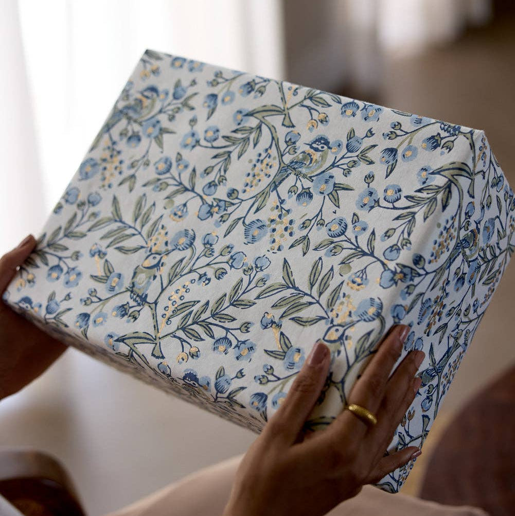 Person holding a floral-patterned box with blurred background