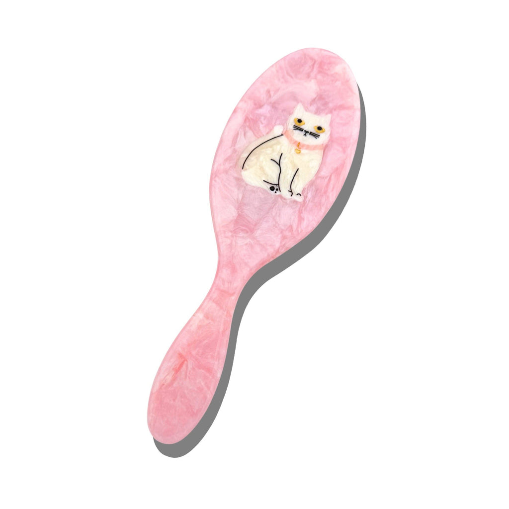 Pink hairbrush with a cat design on a white background