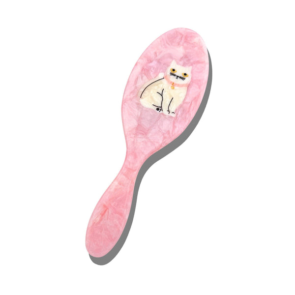 Pink hairbrush with a cat design on a white background