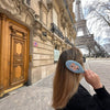 Person with a floral hairbrush in front of the Eiffel Tower