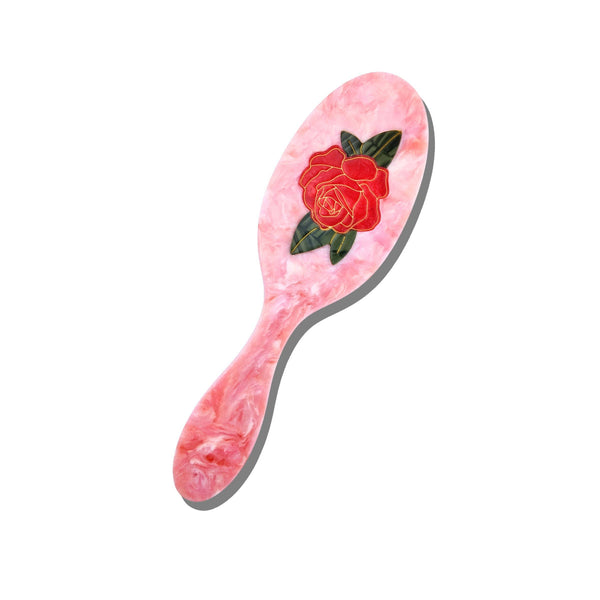 Pink hairbrush with a rose design on a white background