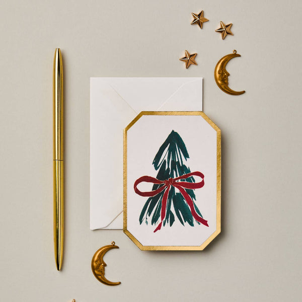 Greeting card with Christmas tree and bow design, gold pen and decorative stars on beige background