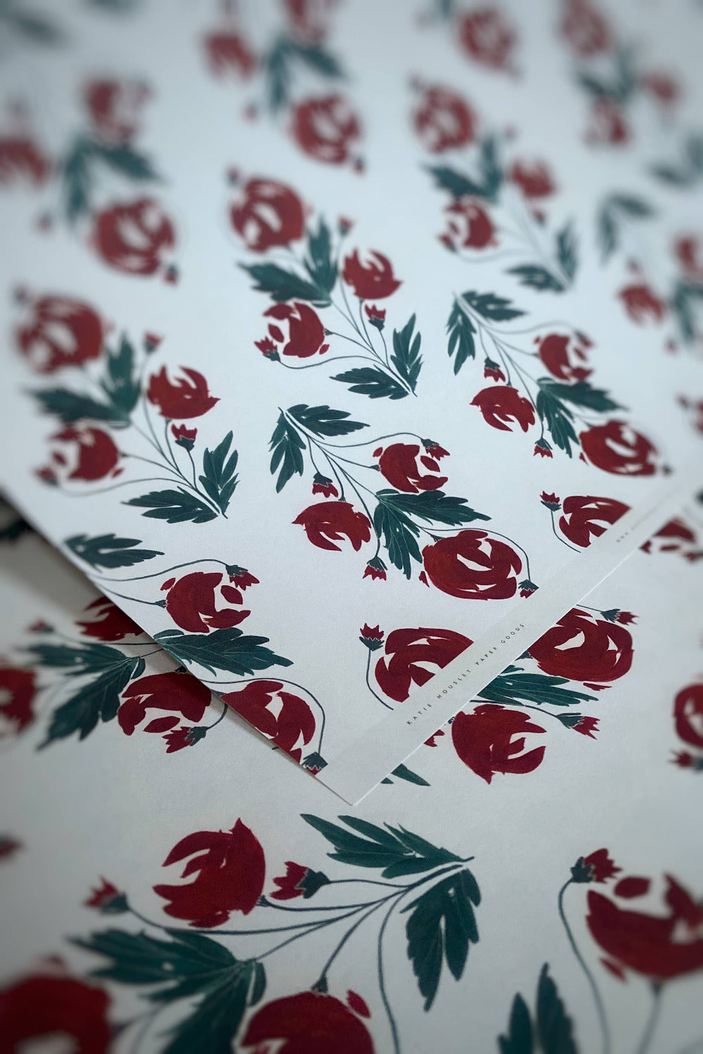 Floral patterned paper with red flowers and green leaves on a white background