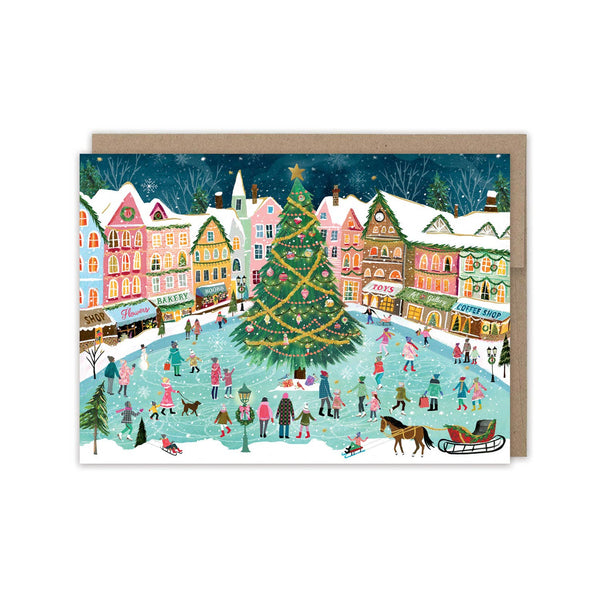 Christmas card with a winter village scene, Christmas tree, and people skating on an ice rink.