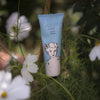 Hand cream tube labeled 'divine hand cream' among flowers