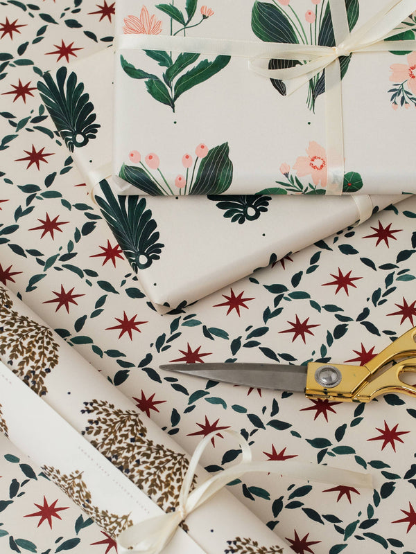 Floral and leaf-patterned wrapping paper with scissors on a matching background