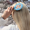 Person with a blue hairbrush with floral design against a cherry blossom background