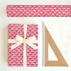 Pink patterned gift wrap with a bow and ruler on a white background