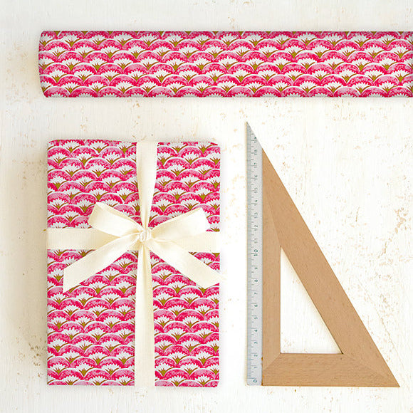 Pink patterned gift wrap with a bow and ruler on a white background
