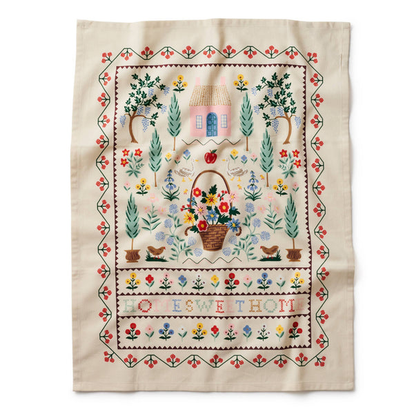 Embroidered fabric with garden scene and text on a white background