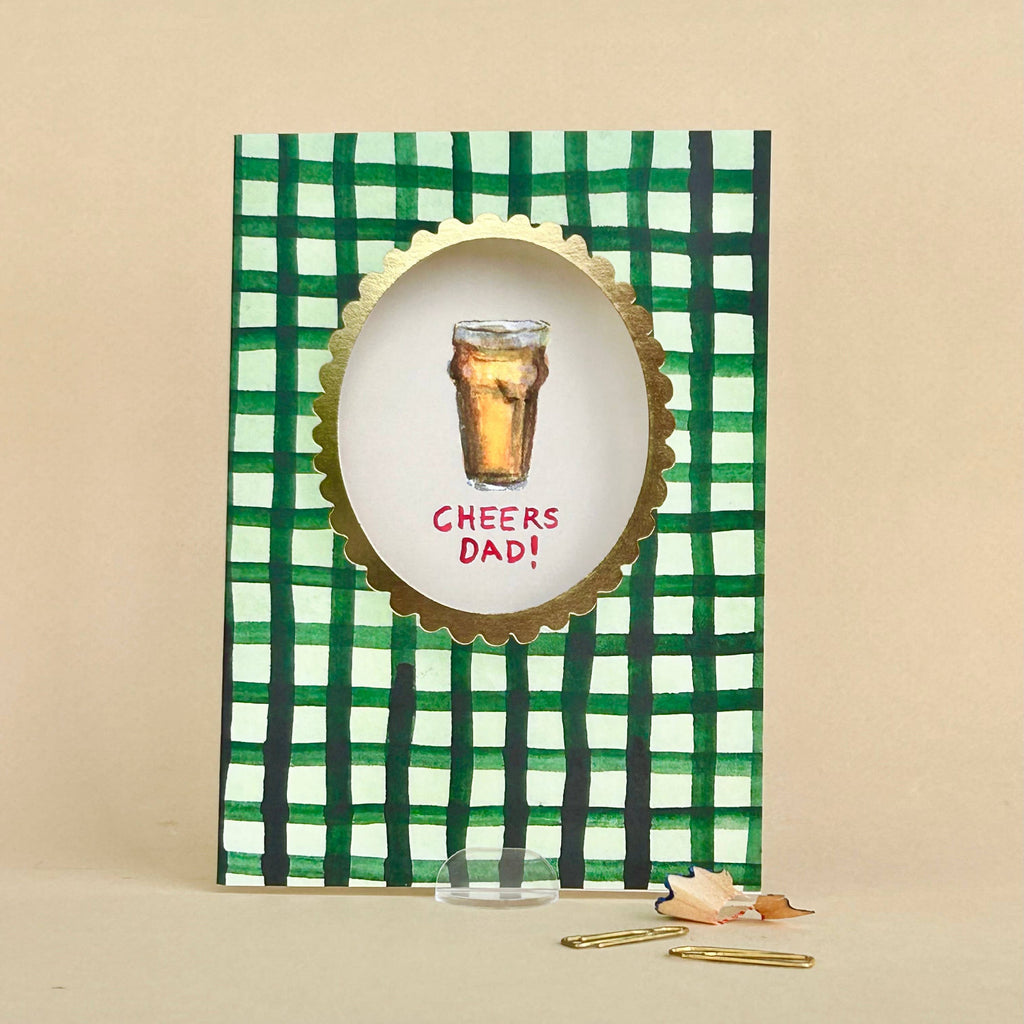 Greeting card with green checkered design, glass of beer, and 'Cheers Dad!' text on a beige background.