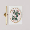 Decorative card with holly design and a pen on a light gray background