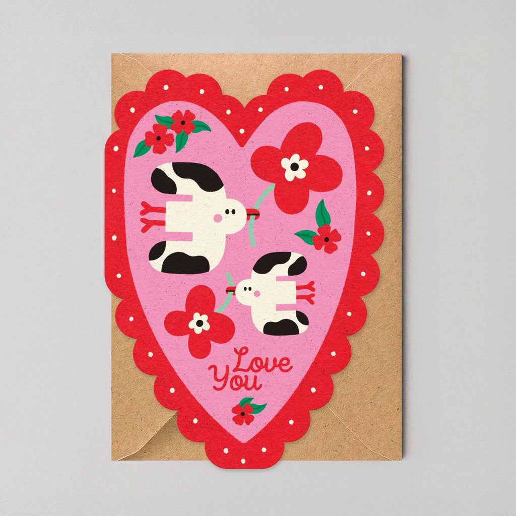 Heart-shaped card with cartoon cows and flowers on a gray background
