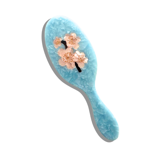 Blue hairbrush with floral design on a white background