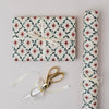 Gift wrapped in patterned paper with a pair of scissors on a light gray background