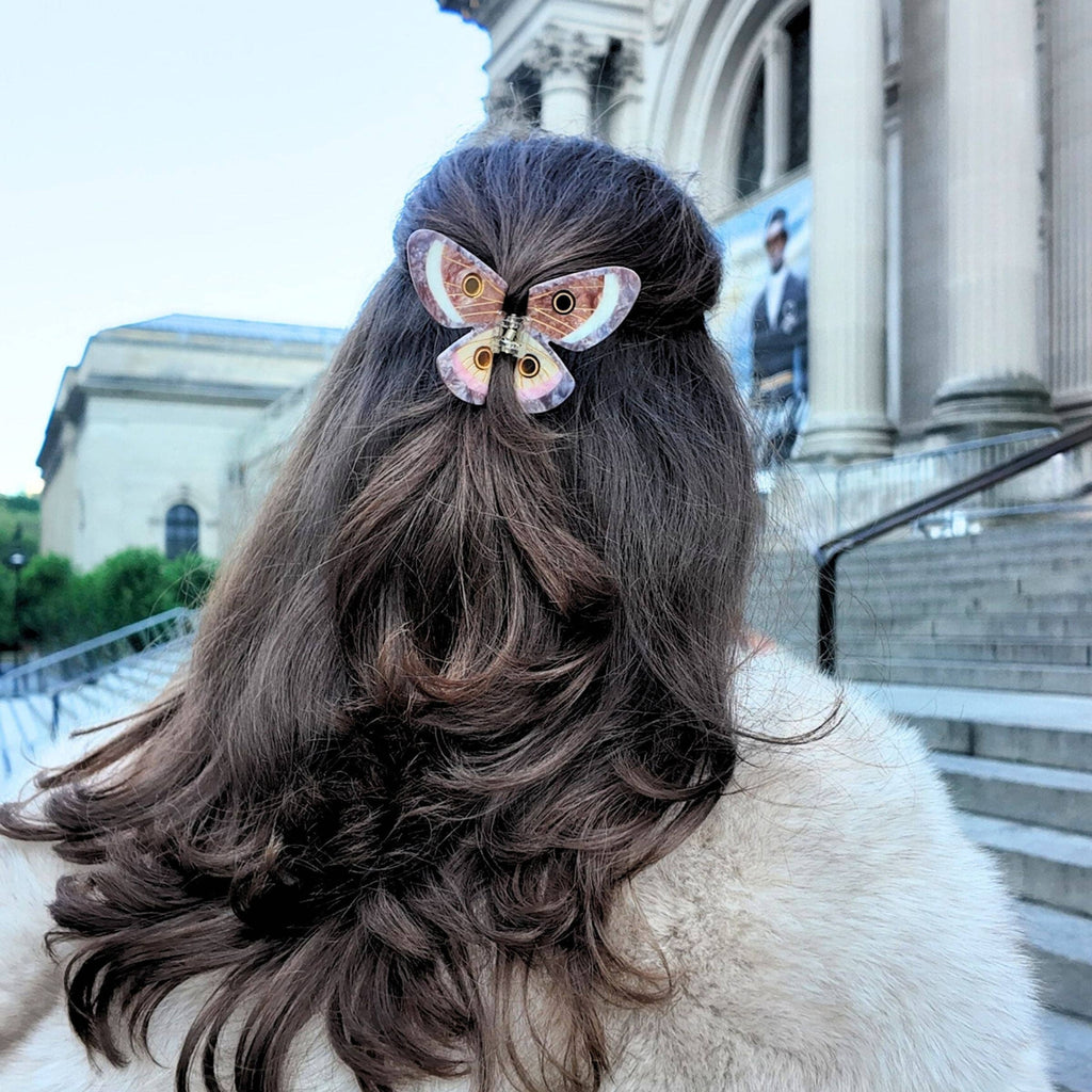 Person with styled hair featuring a decorative hair clip in front of a building